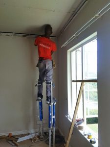 Man On Stilts Doing A Residential Ceiling Installation